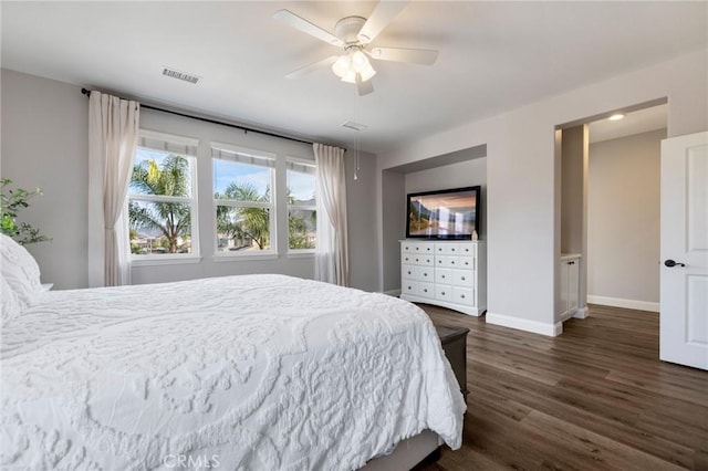 bedroom featuring a ceiling fan, visible vents, dark wood-style floors, and baseboards