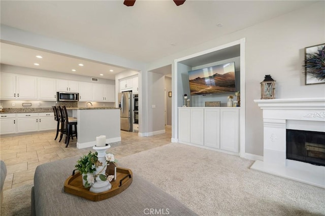 living area featuring a glass covered fireplace, recessed lighting, baseboards, and a ceiling fan