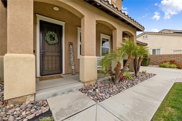 view of exterior entry with a tiled roof and stucco siding