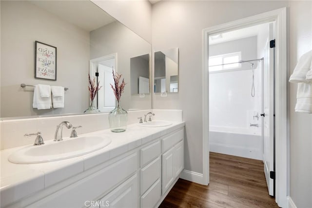 full bath featuring double vanity, tub / shower combination, wood finished floors, and a sink