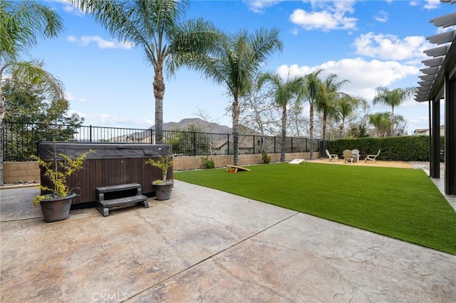 view of patio with a mountain view, a fenced backyard, and a hot tub