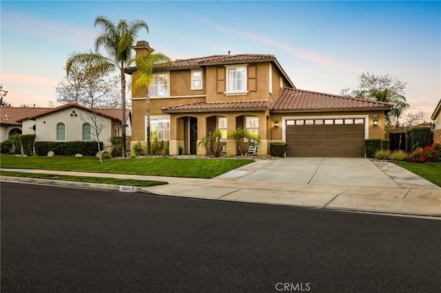 mediterranean / spanish house featuring a yard, stucco siding, concrete driveway, a garage, and a tile roof