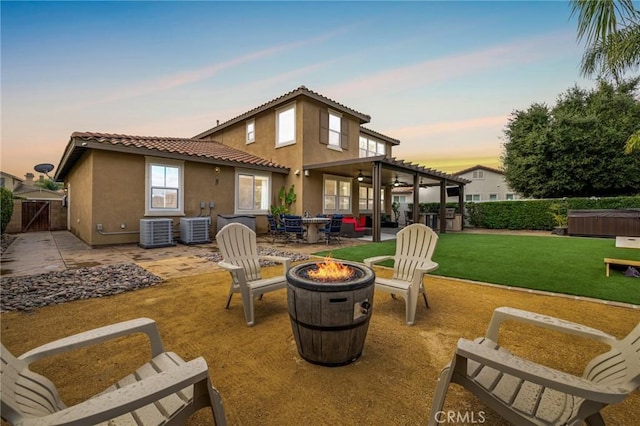 rear view of house with a fire pit, central air condition unit, a patio area, and stucco siding