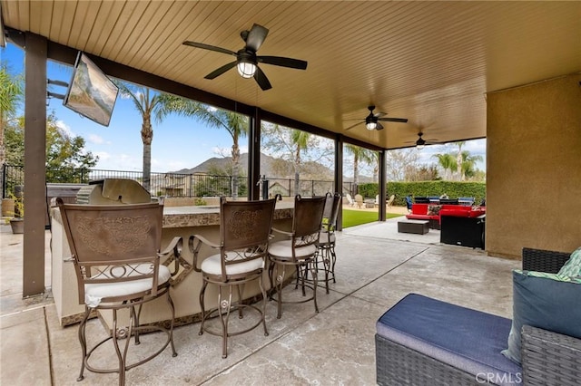 view of patio / terrace with a ceiling fan, outdoor wet bar, area for grilling, and fence