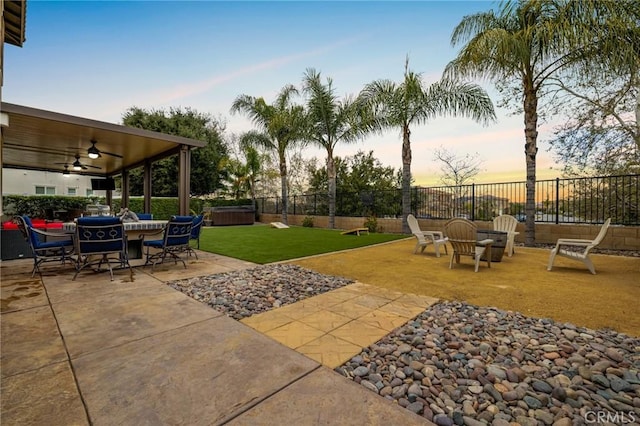 yard at dusk with ceiling fan, a patio, and a fenced backyard