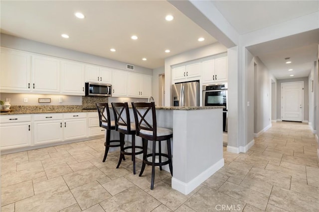 kitchen with white cabinetry, dark stone counters, and stainless steel appliances