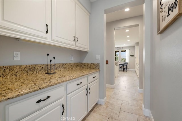 kitchen featuring light stone counters, recessed lighting, white cabinets, and baseboards