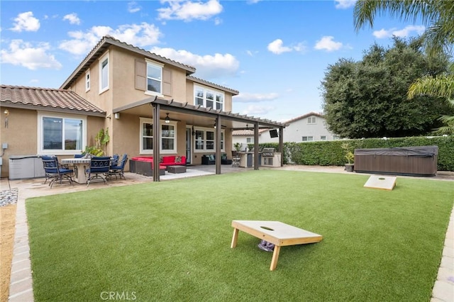 back of property featuring a hot tub, ceiling fan, stucco siding, a lawn, and a patio