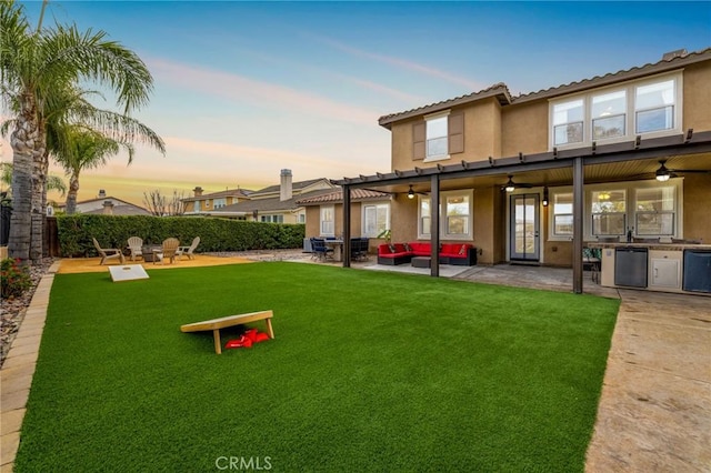 back of house at dusk featuring a patio, a ceiling fan, fence, area for grilling, and stucco siding