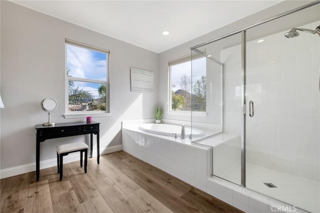 bathroom featuring a bath, wood finished floors, a stall shower, and a wealth of natural light