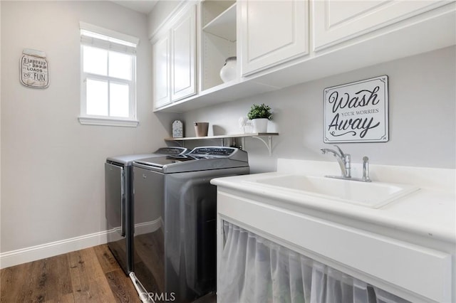 laundry area featuring dark wood-type flooring, baseboards, cabinet space, independent washer and dryer, and a sink