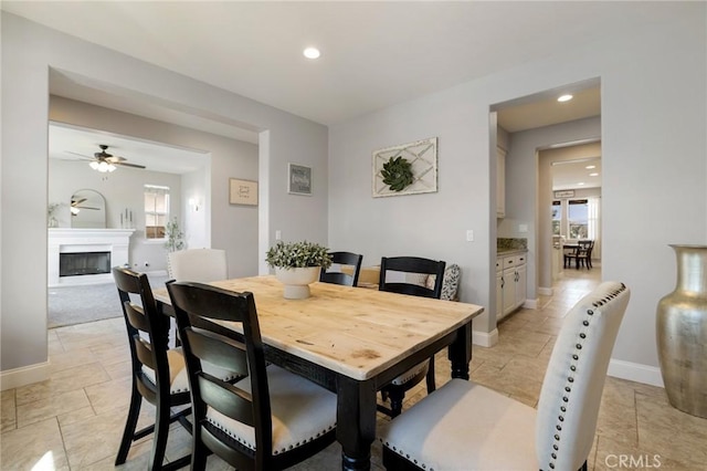 dining room with a glass covered fireplace, recessed lighting, baseboards, and a ceiling fan