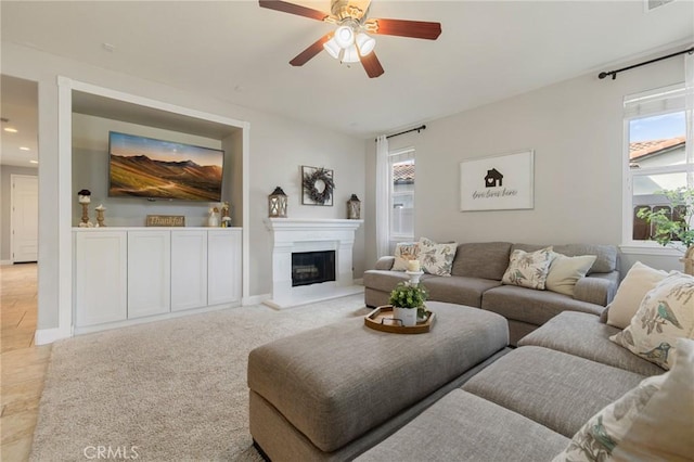 living area featuring a glass covered fireplace, plenty of natural light, a ceiling fan, and recessed lighting