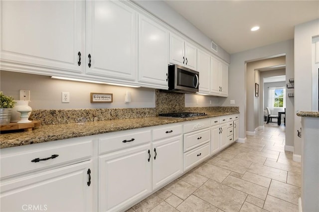 kitchen featuring visible vents, white cabinetry, appliances with stainless steel finishes, baseboards, and light stone countertops