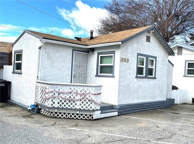 rear view of property with stucco siding and a shingled roof