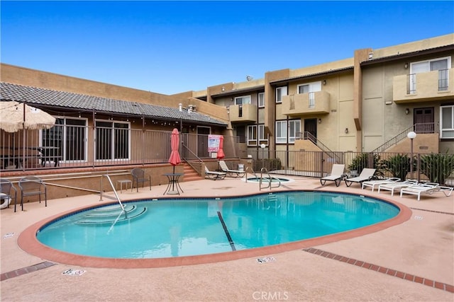 community pool with a patio area and fence