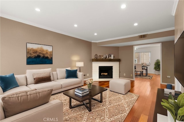 living room featuring recessed lighting, visible vents, ornamental molding, and light wood finished floors