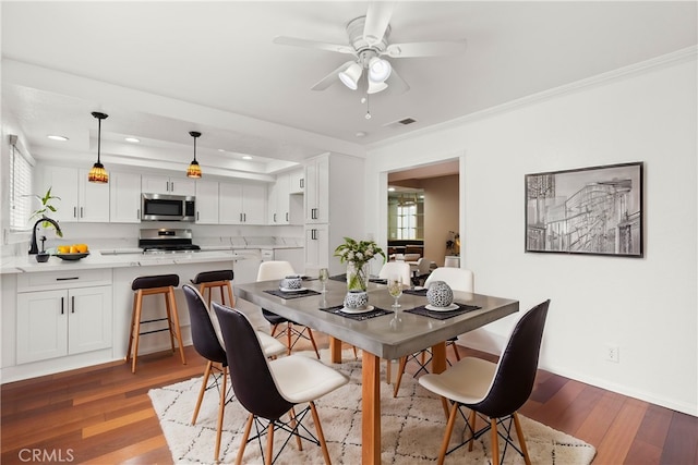 dining room with visible vents, crown molding, ceiling fan, and wood finished floors