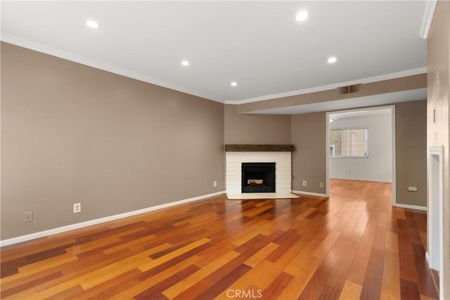 unfurnished living room featuring light wood-style flooring, a fireplace, visible vents, and ornamental molding