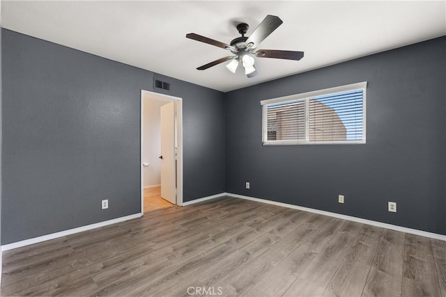 empty room with visible vents, ceiling fan, baseboards, and wood finished floors