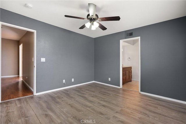 unfurnished bedroom with visible vents, ensuite bathroom, wood finished floors, baseboards, and ceiling fan