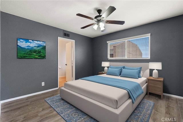 bedroom featuring visible vents, baseboards, wood finished floors, and a ceiling fan