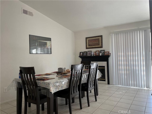 dining room with lofted ceiling, light tile patterned floors, and visible vents