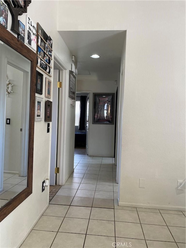 hall featuring light tile patterned floors and baseboards