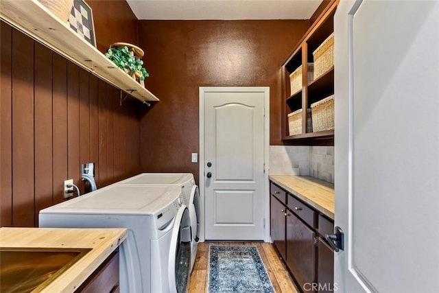 laundry area featuring a sink, cabinet space, independent washer and dryer, and light wood finished floors