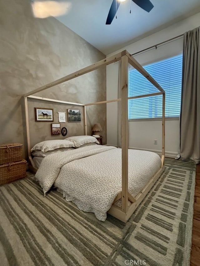 bedroom featuring a high ceiling, ceiling fan, and wood finished floors