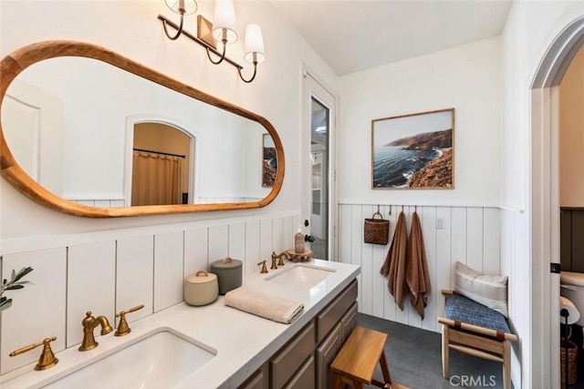 bathroom with double vanity, a wainscoted wall, and a sink