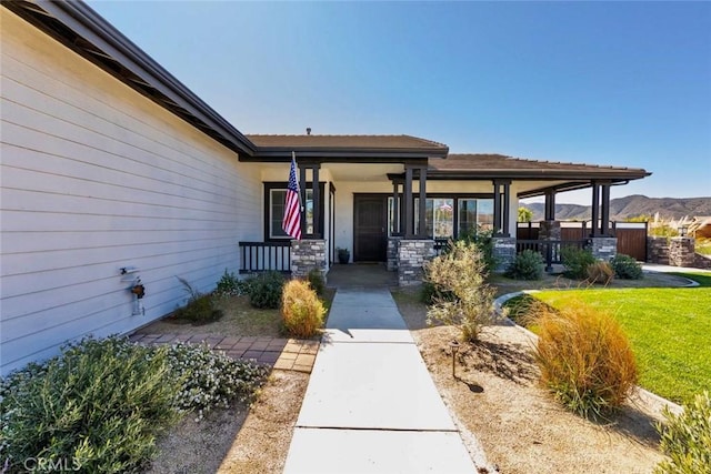 property entrance featuring a mountain view, a yard, and covered porch