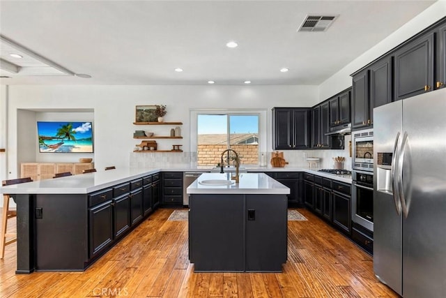 kitchen featuring visible vents, a sink, appliances with stainless steel finishes, a peninsula, and light countertops