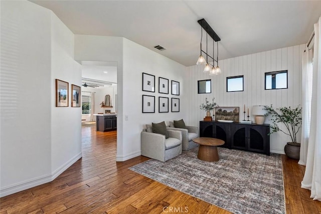 living area with hardwood / wood-style flooring, baseboards, visible vents, and ceiling fan