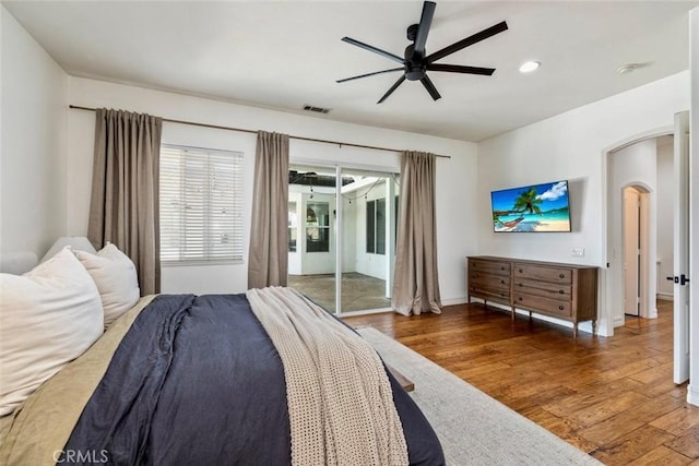 bedroom with wood finished floors, visible vents, arched walkways, ceiling fan, and access to exterior