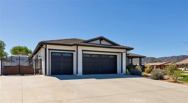 view of front of home featuring concrete driveway, a gate, a mountain view, and an attached garage