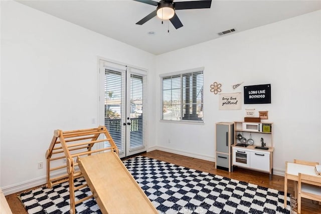 interior space featuring wood finished floors, baseboards, visible vents, ceiling fan, and french doors