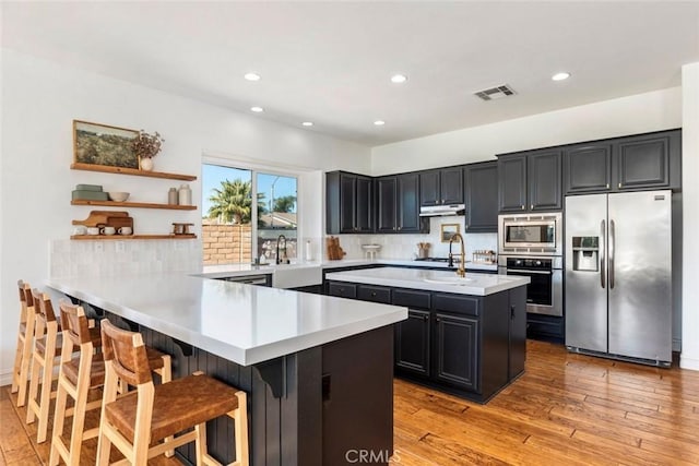 kitchen featuring visible vents, light countertops, appliances with stainless steel finishes, a peninsula, and dark cabinets