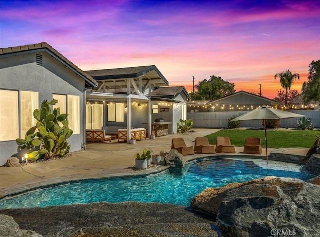 rear view of house featuring stucco siding, a fenced in pool, a fenced backyard, and a patio area