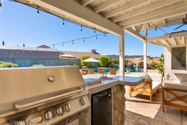 view of patio / terrace featuring fence, outdoor wet bar, a grill, an outdoor pool, and an outdoor kitchen