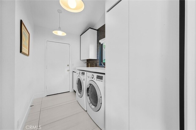 washroom with cabinet space, washing machine and dryer, and baseboards