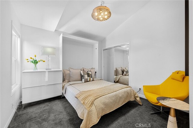 carpeted bedroom featuring a closet, an inviting chandelier, baseboards, and lofted ceiling