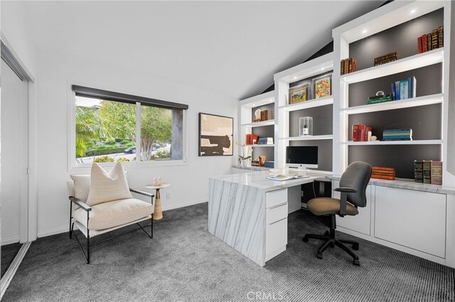 office area featuring lofted ceiling, built in features, baseboards, and dark carpet