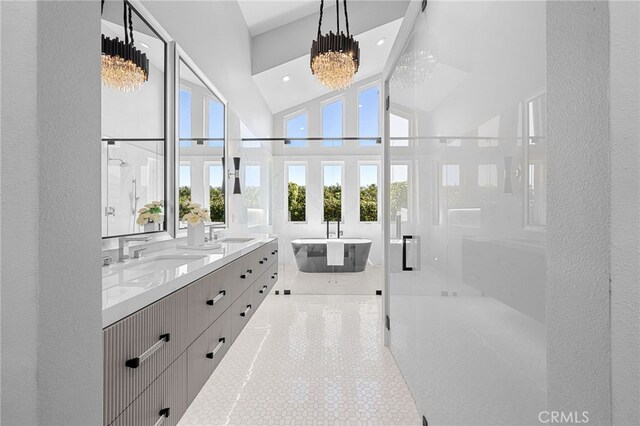 bathroom with a shower stall, a chandelier, a freestanding bath, double vanity, and a sink