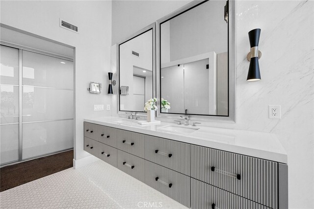 full bathroom with double vanity, visible vents, and a sink