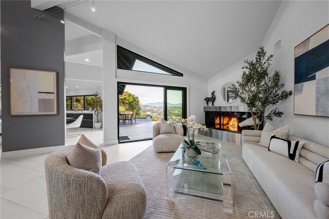 tiled living room with visible vents, a warm lit fireplace, and high vaulted ceiling