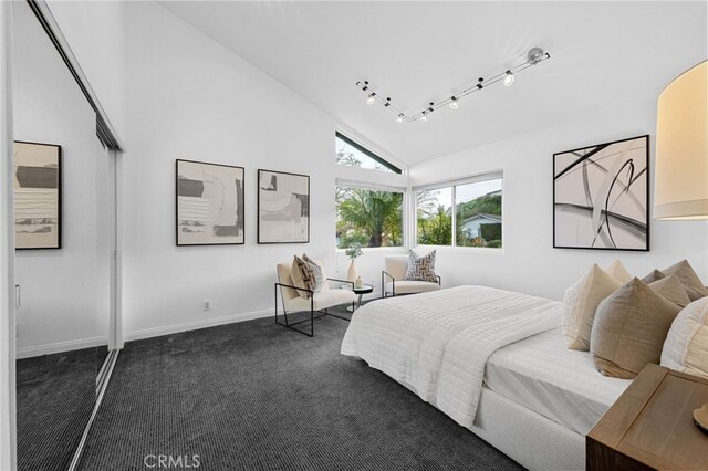 bedroom with track lighting, dark carpet, high vaulted ceiling, and baseboards