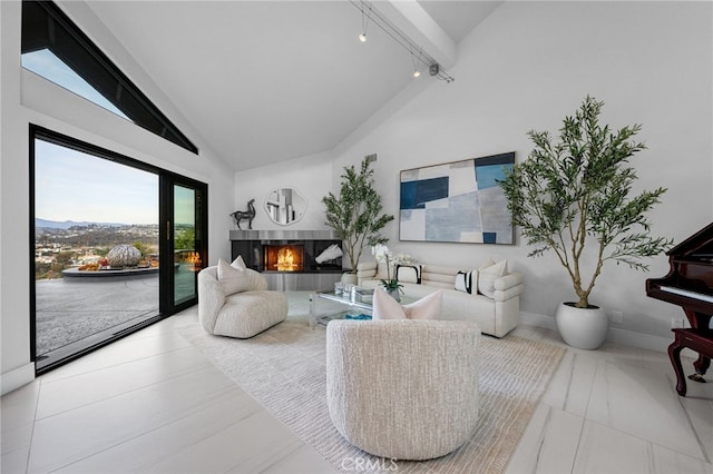 living area featuring baseboards, a multi sided fireplace, high vaulted ceiling, and rail lighting