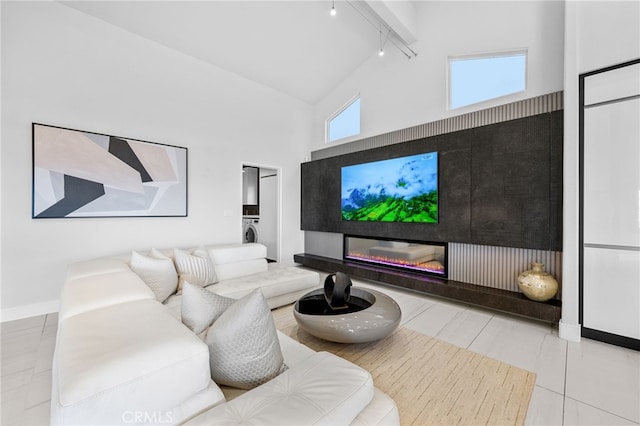32252 Azores Rd, Dana Point, CA 92629 - living room with washer / clothes dryer, rail lighting, high vaulted ceiling, baseboards, and a glass covered fireplace