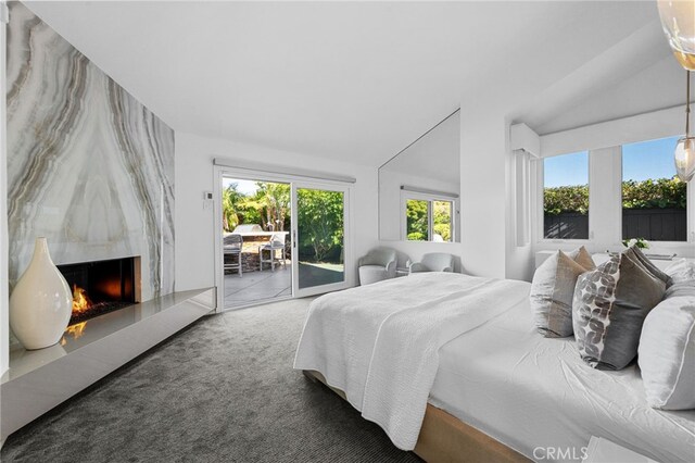 bedroom featuring access to exterior, lofted ceiling, carpet, and a high end fireplace